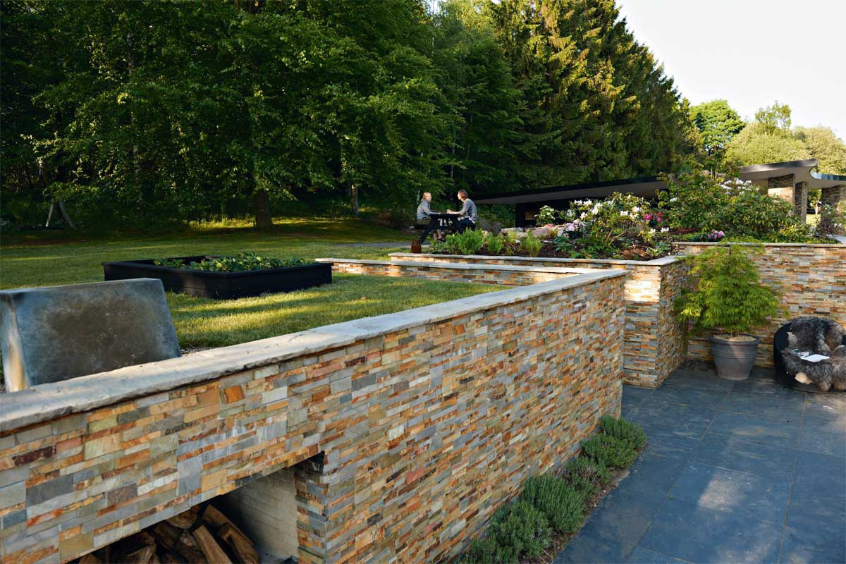 Norstone Ochre XLX used on a large retaining wall seperating an upper garden area and a lower stone patio
